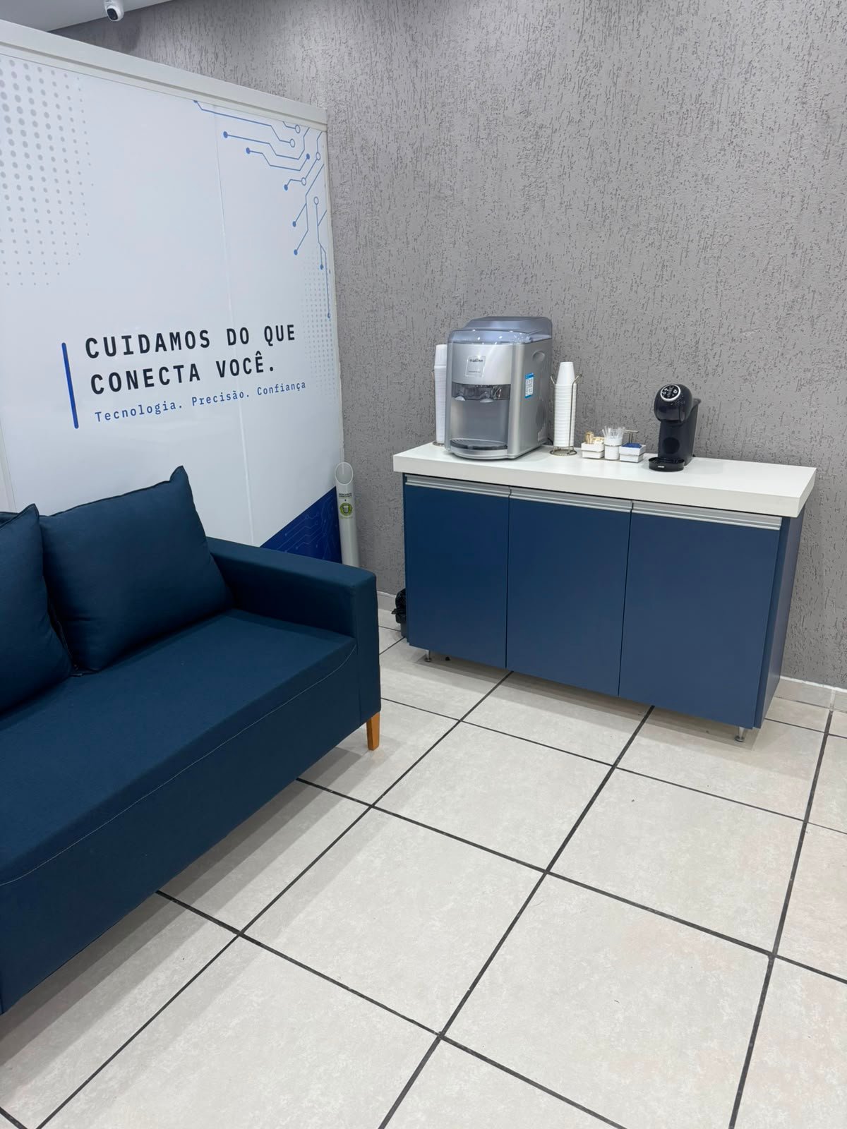 Área de descanso com sofá, café e água para clientes
